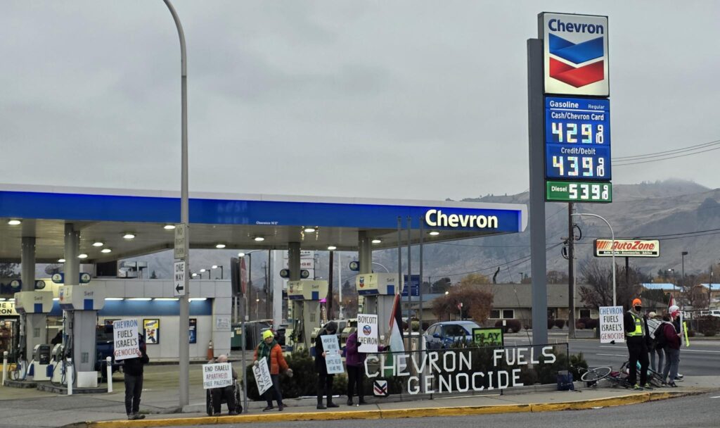 Protesters holding signs outside of the Wenatchee Chevron gas station.